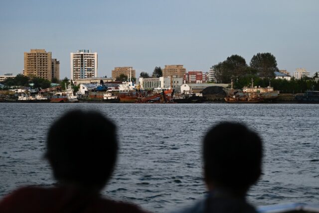 Chinese tourists watch the North Korean border on the Yalu river in the Chinese border tow