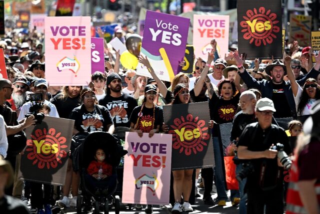 Crowds hold up banners during a "Walk for Yes" rally in Melbourne ahead of the referendum