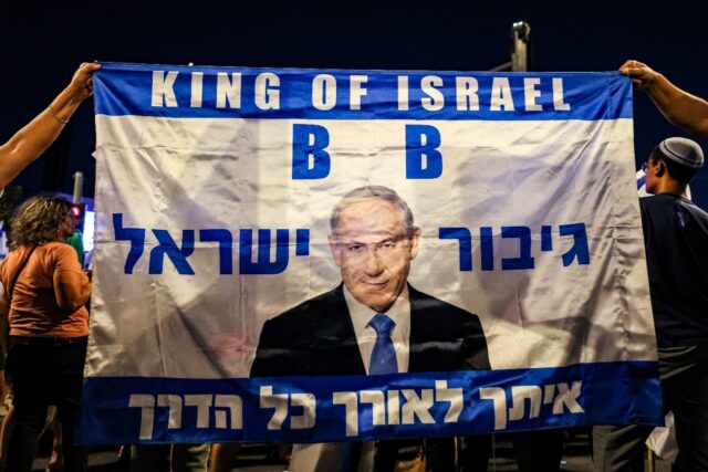Demonstrators hold a banner showing an image of Israel's Prime Minister Benjamin Netanyahu