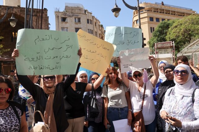 School teachers lift placards during a sit-in outside Lebanon's parliament protesting poor