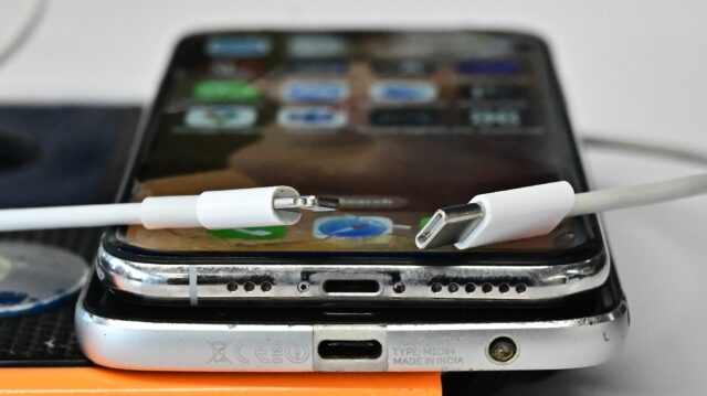 A USB-C charger (R) and a traditional Apple Lightning charger (L) are seen on an Apple iPh