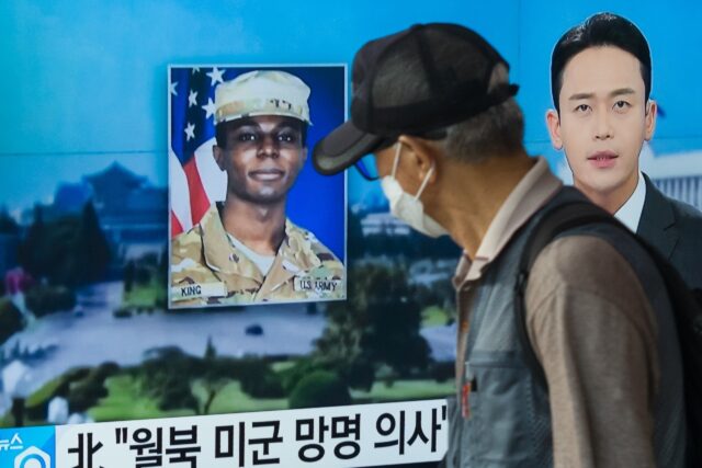 A man walks past a television news broadcast featuring a photo of US soldier Travis King i