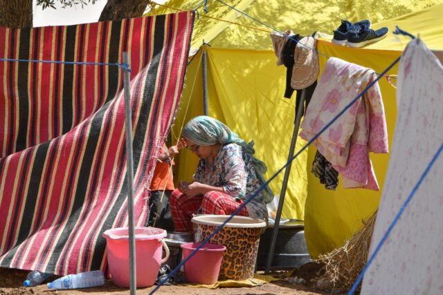 A woman sits outside her tent at a camp for locals displaced by a devastating earthquake i