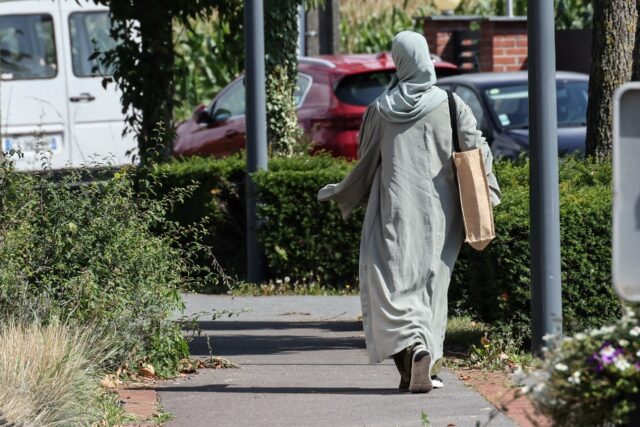 A woman wearing an abaya dress walks through the streets of Lille, northern France, on Aug
