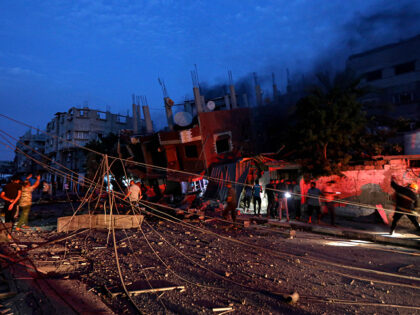 People gather as Palestinian civil defense crews try to extinguish fire in a house that wa
