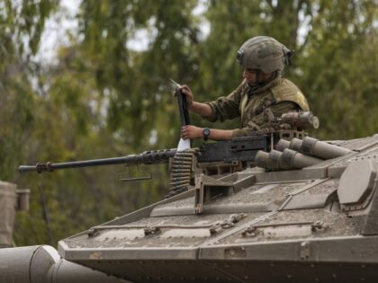 An Israeli soldier works on a tank at a staging ground near the Israeli Gaza border, south