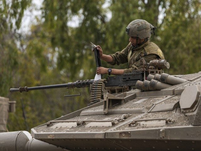 An Israeli soldier works on a tank at a staging ground near the Israeli Gaza border, south
