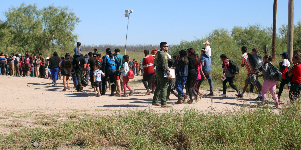 Eagle Pass Border Patrol agents march a large group of migrants from the border crossing to a transportation point. (Randy Clark/Breitbart Texas)