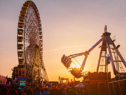 Fairground rides at sunset - stock photo