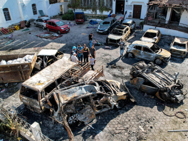 This aerial view shows people standing before destroyed buildings at the site of the Ahli