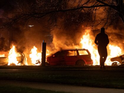 A protester stands next burning cars in Malmo on April 17, 2022. - Plans by a far-right group to publicly burn copies of the Koran sparked violent clashes with counter-demonstrators for the third day running in Sweden, police said on April 17, 2022. - Sweden OUT (Photo by Johan NILSSON …