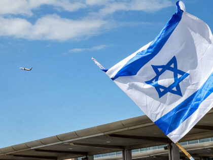 A Ryanair passenger aircraft takes off while a demonstrator waves an Israeli flag during a