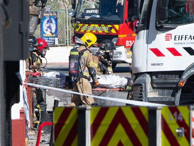 Firefighters carry out a stretcher as at least eleven people were killed in a fire at the