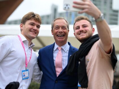 Delegates pose for a photograph with former Leader of the Brexit Party, Nigel Farage (C),