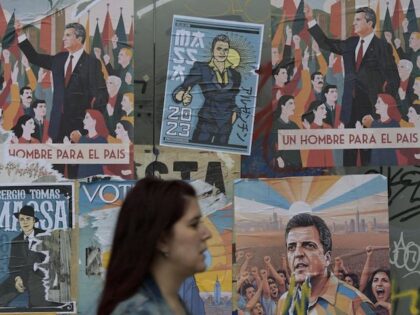A woman walks past electoral propaganda of Economy Minister and presidential candidate of