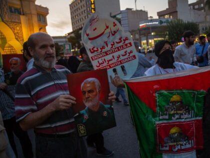 10/07/2023 Tehran, Iran. Two supporters of the Iranian regime hold a picture of Ghasem Sol