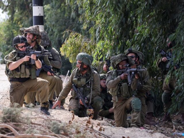 TOPSHOT - Israeli soldiers take up position in Kfar Aza, in the south of Israel, bordering