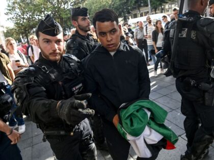 A protestor holding a Palestinian flag is led away by French Gendarme Police Officers dur