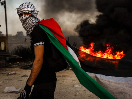 A Palestinian dons a Palestinian flag during while protesting Israeli occupation in the West Bank, as protesters are met with tear gas, flashbang and live fire from Israeli forces, in Beit El area of Ramallah, Israel, Friday, Oct. 13, 2023. Tensions are rising all across Israel and Palestinian Territories as …