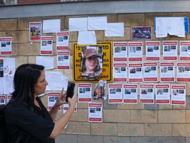 A woman takes a photograph with her mobile phone of images of Israeli hostages snatched by
