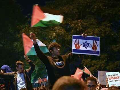 A man holds a placard representing an Israeli flag with a Nazi Swastika inside the Star of