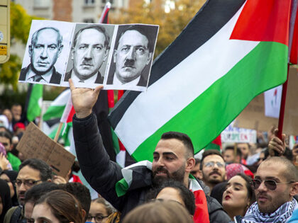 Demonstrators hold a Palesitinan national flag and a sign that shows portrait of Israeli Prime Minister Benjamin Netanyahu converting to Nazi Germany's leader Adolf Hitler during a rally called 'Gaza: stop massacres, stop impunity' in support of Palestinians and to demand for an immediate ceasefire, in Brussels, on October 22, …