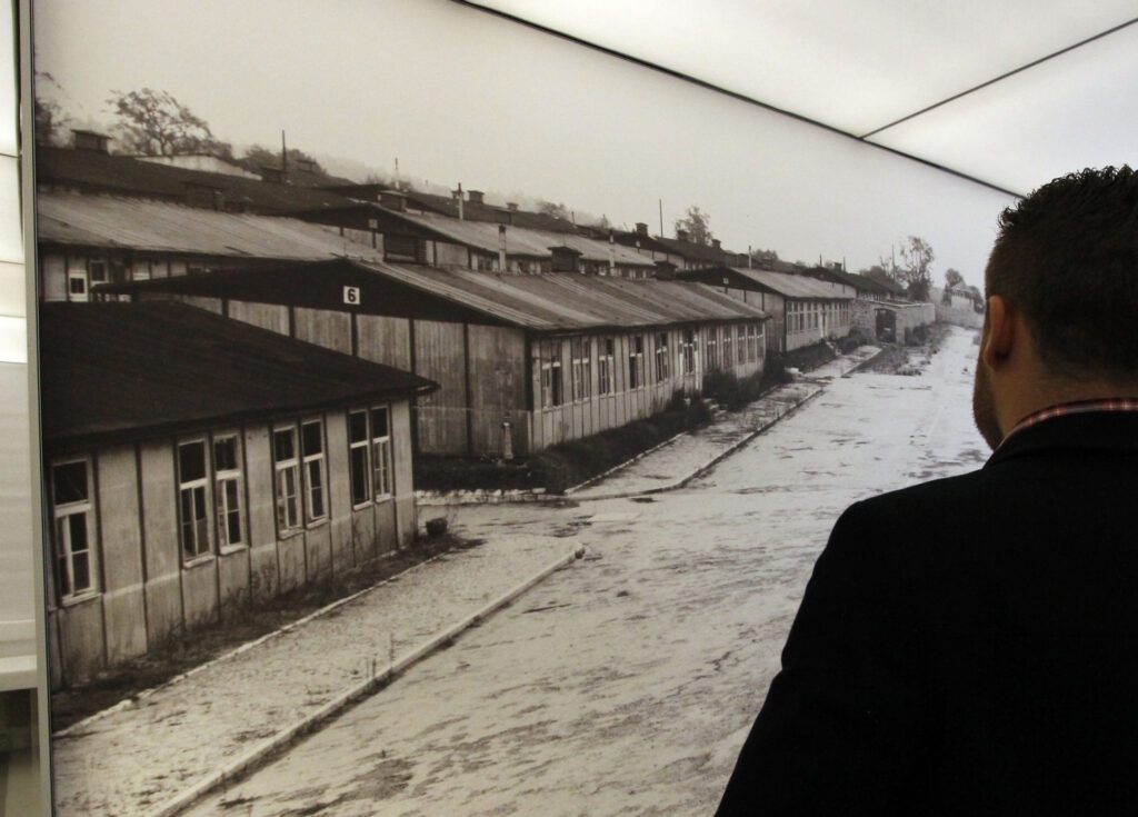 In this picture taken Thursday, May 2, 2013 a visitor looks at a poster of the former Nazi concentration camp of Mauthausen during a press preview in a new memorial room in the former camp in Mauthausen, Austria. The concentration camp was liberated by U.S. troops on May 5, 1945. (AP Photo/Ronald Zak)