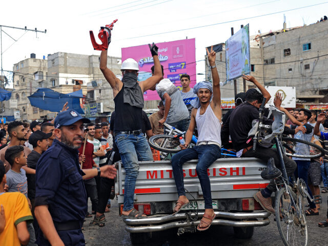 Palestinians celebrate their return after crossing the border fence with Israel from Khan Yunis in the southern Gaza Strip on October 7, 2023. Barrages of rockets were fired at Israel from the Gaza Strip at dawn as militants from the blockaded Palestinian enclave infiltrated Israel, with at least one person …