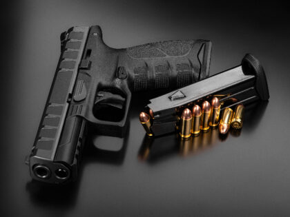 Black modern gun and ammunition for it on a dark reflective surface. Short-barreled weapons for sports and self-defense. Armament for police units, special forces and the army. Black background - stock photo