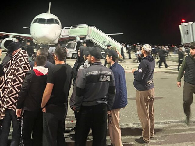 People in the crowd walk shouting antisemitic slogans at an airfield of the airport in Mak