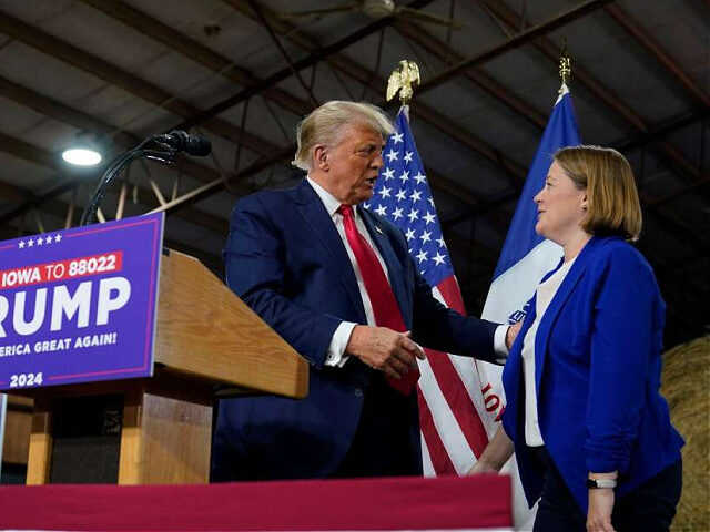 Former President Donald Trump talks with Iowa Attorney General Brenna Bird during a commit