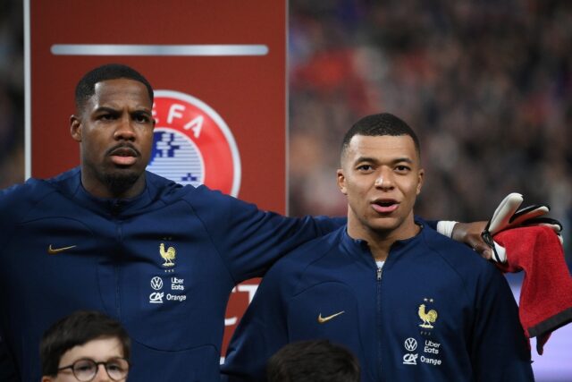 Mike Maignan (L) and Kylian Mbappe sing the French anthem together ahead of a match agains