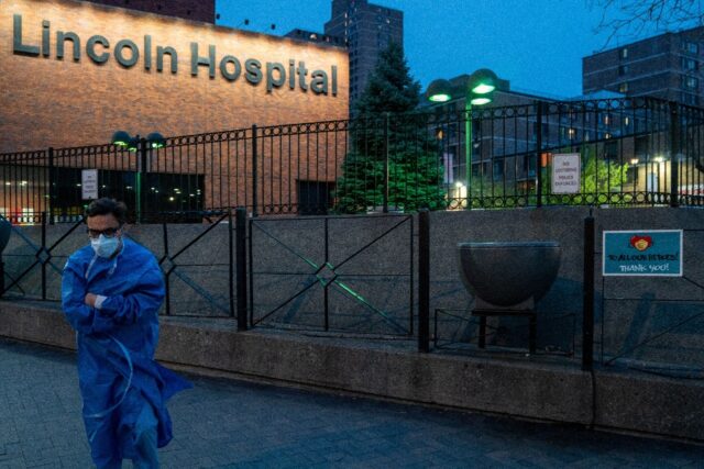 A member of the medical staff walks by a sign thanking medical workers at Lincoln Hospital