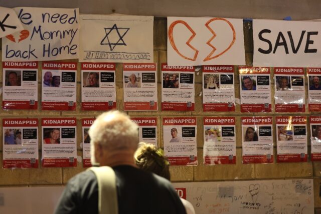 People gather next to a wall in Tel Aviv bearing the portraits of those kidnapped during t