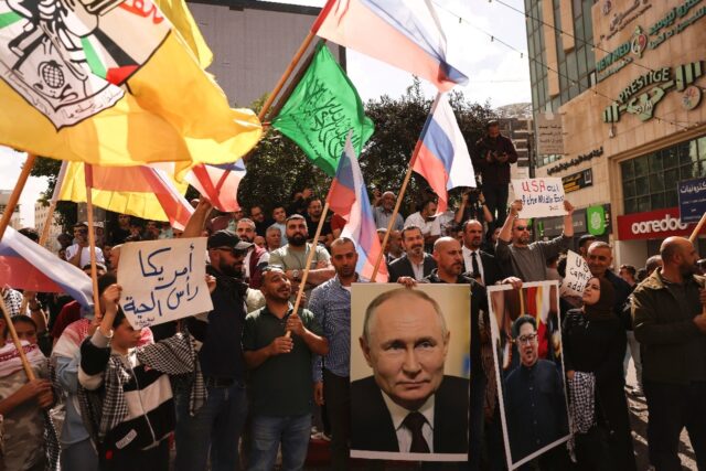 People wave Russian, Palestinian, Fatah and Hamas flags and carry portraits of Russia's Pr