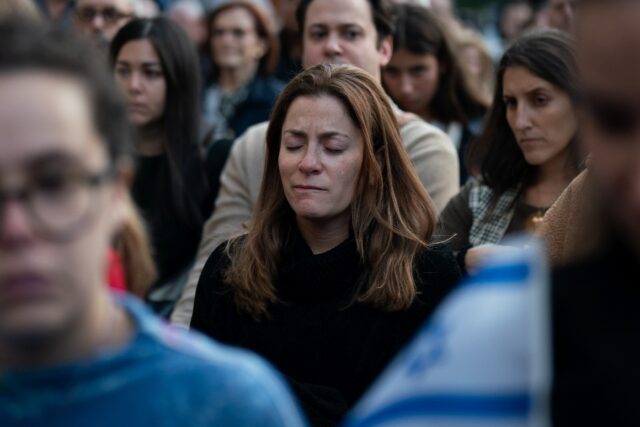 A person cries during a prayer service and candlelight vigil for Israel at Temple Emanu-El