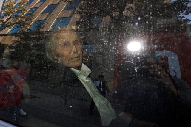 Seen through a police vehicle window, Canadian-Finnish fashion mogul Peter Nygard leaves a