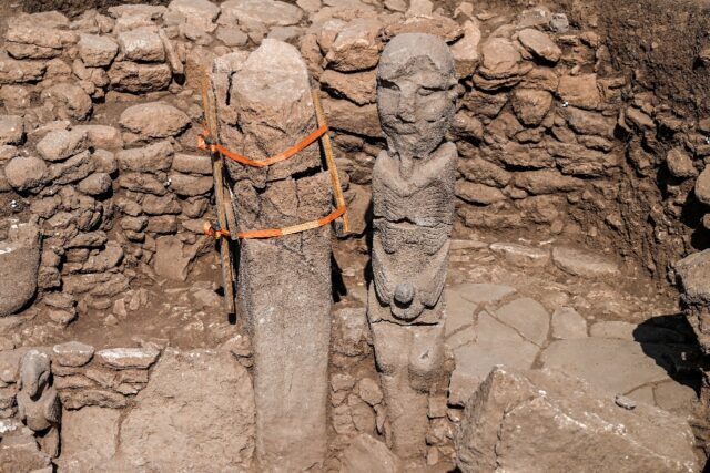 For researchers, the carved statue of a man holding his phallus with two hands while seate