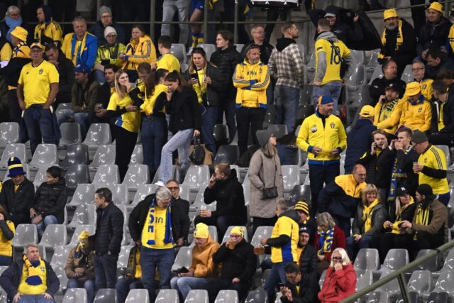 Sweden supporters wait inside the ground after their team's game against Belgium was stopp