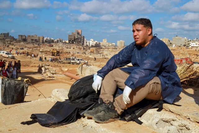 A volunteer sits on the rubble of a building in the aftermath of the flood disaster in Lib