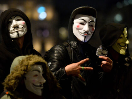 Masked protesters in Trafalgar Square, London, take part in the Million Mask March bonfire