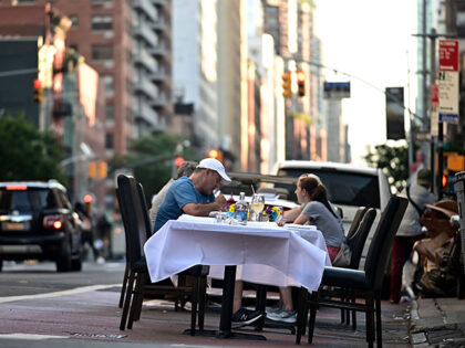Guests sit outside a restaurant, which extended it's outdoor area by setting tables o