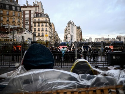 Cordoned by French Gendarmes mobile riot unit, migrants queue to embark buses for temporary shelter during the evacuation of their makeshift camp gathering hundreds, mostly Afghan, in Paris on November 17, 2022. (Photo by Christophe ARCHAMBAULT / AFP) (Photo by CHRISTOPHE ARCHAMBAULT/AFP via Getty Images)