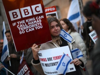 Protesters holding placards and Israeli flags join a gathering outside the headquarters of