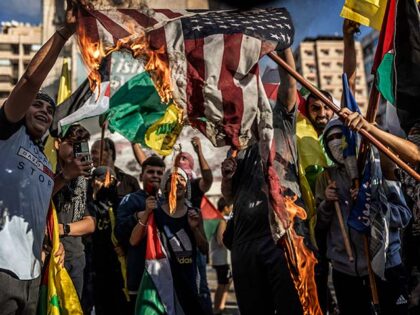 Young supporters of Hezbollah burn a US flag during a rally in support of Palestinians in
