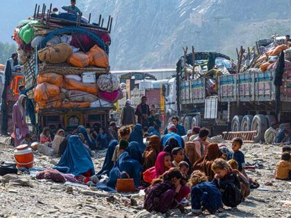 Afghan refugees sit near trucks on their arrival from Pakistan at the Afghanistan-Pakistan