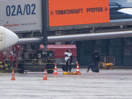 HAMBURG, GERMANY - NOVEMBER 5: A woman wrapping the hostage in a blanket, while the hostage taker is surrendering on the tarmac at Hamburg Airport on November 5, 2023 in Hamburg, Germany. The hostage taker surrendered, after a standoff with the police, after driving his car through a perimeter gate, …