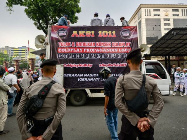 Policemen stand guard as Indonesian Muslims take part in a protest in front of the police headquarters in Jakarta on November 10, 2023 to demand the cancellation of the incoming November 15 concert by British rock band Coldplay, whom protesters say are supportive of LGBT rights, which goes against Muslim …