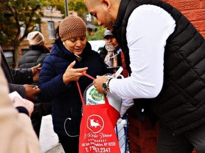 NEW YORK, NEW YORK - NOVEMBER 21: Assemblyman Juan Ardila places a frozen turkey in a bag