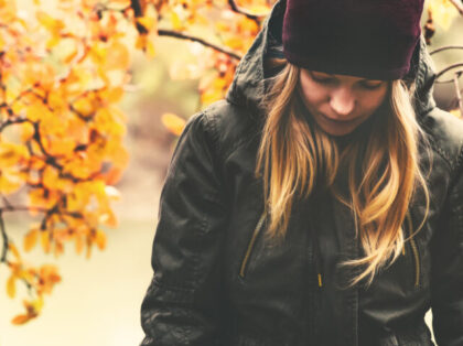 Sad Woman walking in park with autumn leaves on background outdoor Seasonal melancholy Lifestyle concept